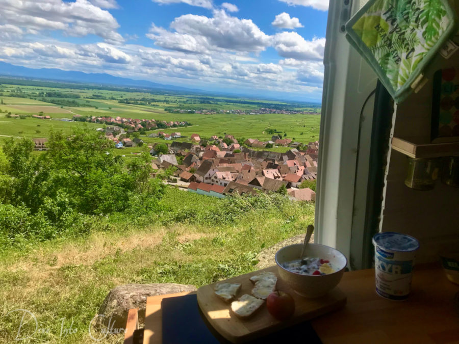 Vanlife Frankreich. Mit offener Schiebetür über den romantischen Dörfern des Elsass. Frühstück mit Ausblick.